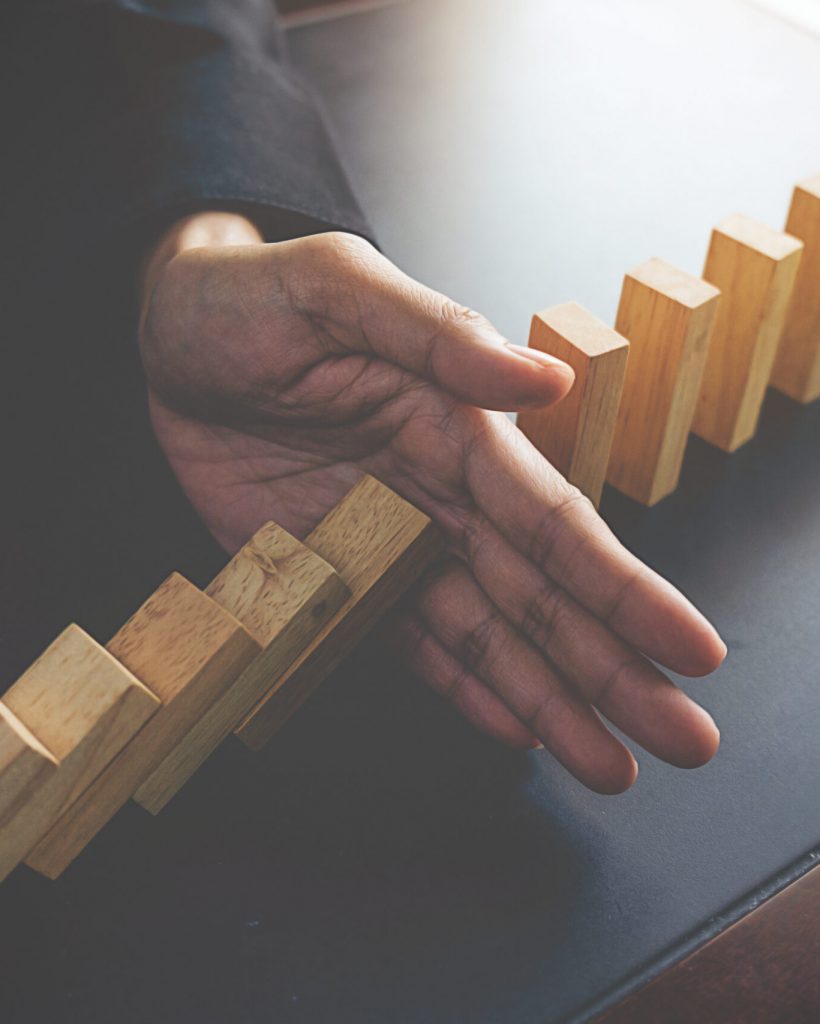 Problem Solving,Close up view on hand of business woman stopping falling blocks on table for concept about taking responsibility.